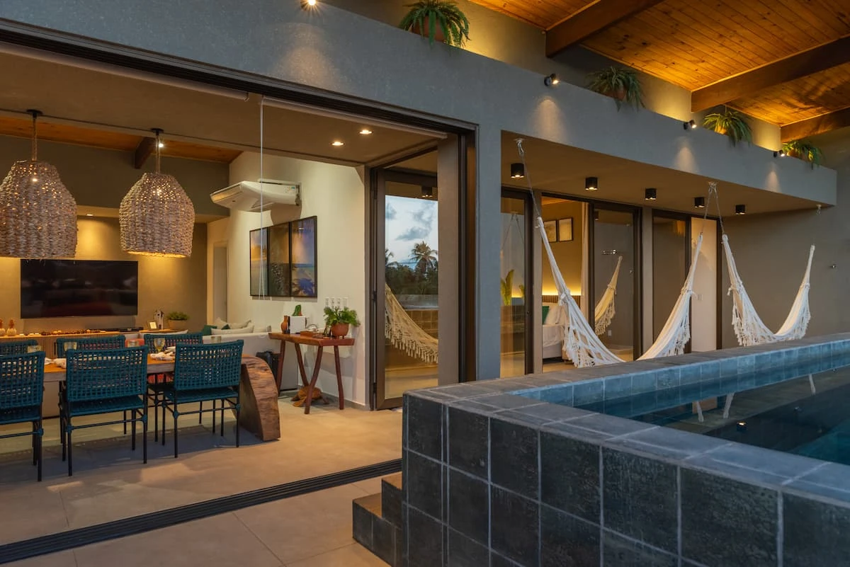 Fim de tarde na cobertura: piscina, área gourmet e redes sob o telhado de madeira.