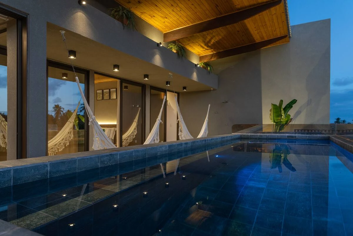 Piscina iluminada ao entardecer, com as redes ao fundo.