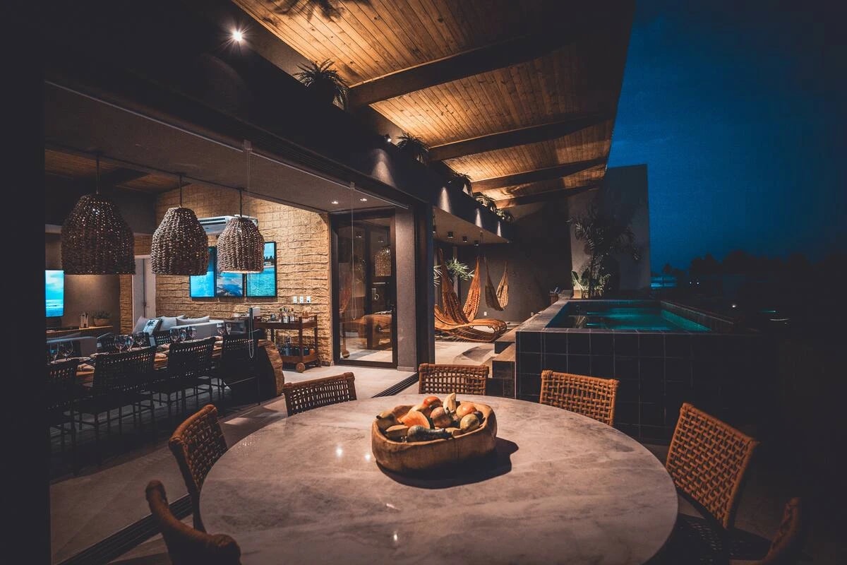 Sala de jantar redonda, sob o teto de madeira, ao anoitecer.